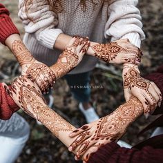 three people holding their hands together with henna tattoos on them