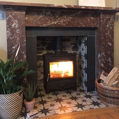 a wood burning stove sitting inside of a living room next to potted plants and a wicker basket