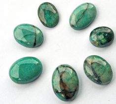 six green stones arranged in a circle on a white surface