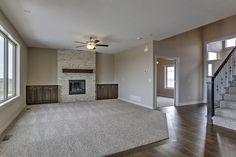 an empty living room with wood flooring and fireplace in the center, surrounded by large windows