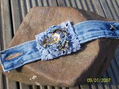 an old pair of blue jeans with a flower on it sitting on top of a rock