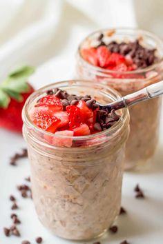 two jars filled with chocolate and strawberries on top of a white table next to a strawberry