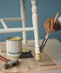 someone is painting a chair with paintbrushes and some other things on the table