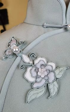 the back of a dress with flowers and pearls on it's lapel collar