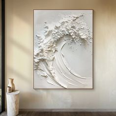 an abstract painting hangs on the wall next to a vase