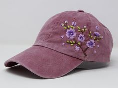 a pink hat with purple flowers embroidered on the front and side, sitting on a white surface