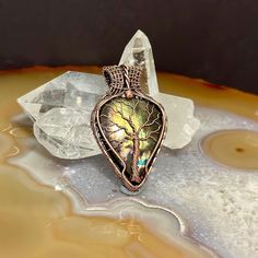 a piece of jewelry sitting on top of a table next to a crystal rock and some water