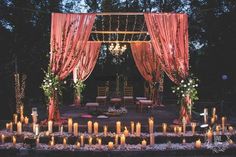 an outdoor wedding setup with candles and draping on the ground, surrounded by greenery