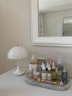 a vanity with various skin care products and a white lamp on the counter in front of a mirror