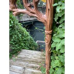 a wooden mirror sitting on top of a wooden floor next to a lush green wall