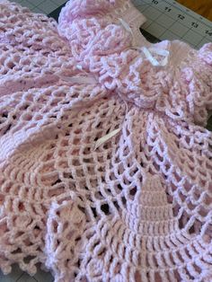 a pink crocheted blanket laying on top of a cutting board