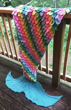 a mermaid tail made out of paper sitting on top of a wooden deck