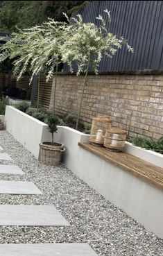 an outdoor garden with stone walkways and potted plants on the side of it