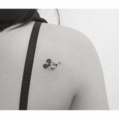 the back of a woman's shoulder with a mickey mouse tattoo