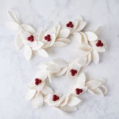 some white flowers and red berries are on a marble counter top, with the letter d spelled out