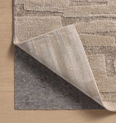 an area rug that has been placed on top of a wooden floor with a beige and gray color scheme