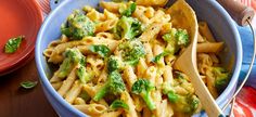 a blue bowl filled with pasta and broccoli on top of a wooden table