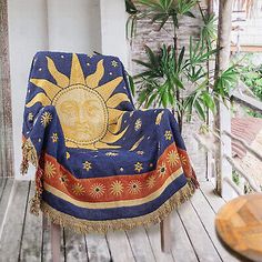 a sun and moon blanket sitting on top of a wooden deck next to a potted plant