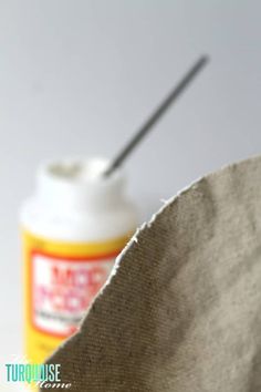 a bottle with a straw sticking out of it sitting next to a cloth bag on a table