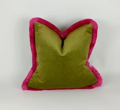 a green and pink pillow on a white background