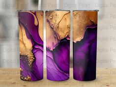 three purple and gold vases sitting on top of a wooden table next to each other