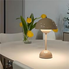 a white table with a lamp and some yellow flowers