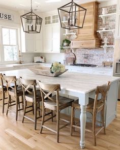 a kitchen with white cabinets and an island in the middle, surrounded by wooden chairs