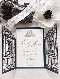 the wedding stationery is laid out on a white tablecloth with black and gold accents