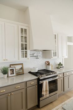 a kitchen with white cabinets and stainless steel stove top oven in the middle of it