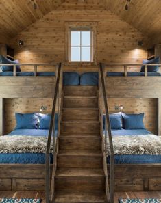 bunk beds in a cabin with stairs leading up to the top floor and another bed below