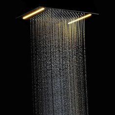 a shower head with the light on and water running down it's side, in front of a black background