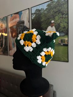 a crocheted hat with yellow and white flowers is on a mannequin head