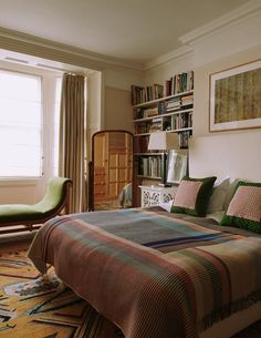 a bed sitting in a bedroom next to a book shelf filled with lots of books