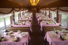 a dining car on a train with pink tablecloths