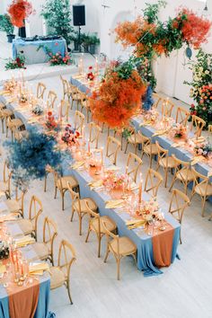 a long table set up with blue linens and orange flowers