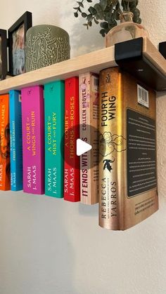 a book shelf with books on it and a potted plant in the corner next to it