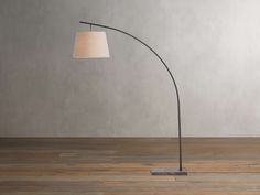 a floor lamp with a white shade on it and a wooden floor next to it