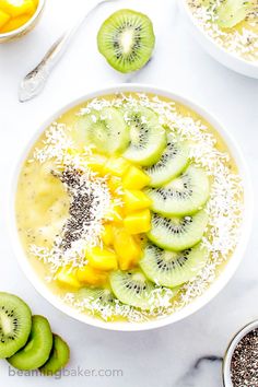 two bowls filled with fruit and oats on top of a white table next to sliced kiwis