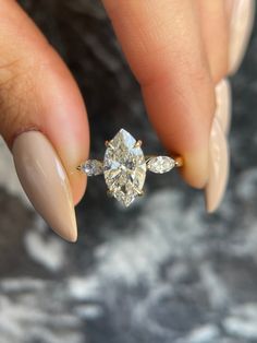 a woman's hand holding an engagement ring with diamonds on the top and bottom