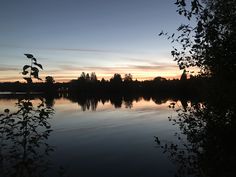 the sun is setting over a calm lake