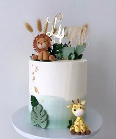 there is a cake decorated with animals and leaves on the top tier, along with a toy giraffe sitting next to it