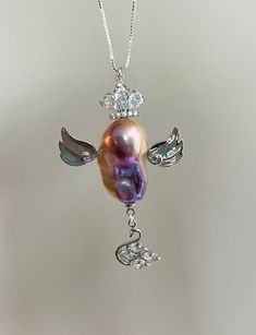 Elevate your elegance with this exquisite necklace that features a unique pendant designed to resemble an angel, featuring a lustrous baroque pearl. This stunning blend of natural beauty and exquisite craftsmanship floats with two large silver wings, with a dangling crystal swan and a queen crown on the top, providing a harmonious balance to the overall design. Whether you seek a distinctive touch for your evening attire or a fresh accent for your everyday jewelry, this piece is a perfect additi A Queen Crown, Baroque Pearl Pendant, Fairy Pendant, Silver Wings, Queen Crown, Pearl Charms, Unique Pendant, Pendant Design, An Angel