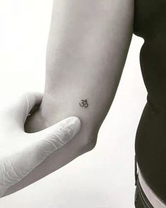 a person with a small tattoo on their left arm holding the other hand up to her wrist