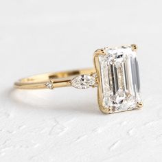 an emerald cut engagement ring with two side stones