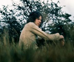 a man sitting in tall grass next to trees