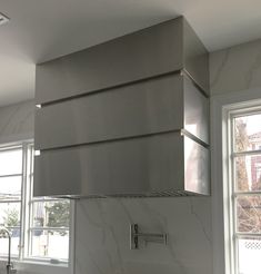 a stove top oven sitting inside of a kitchen next to two windows and a sink