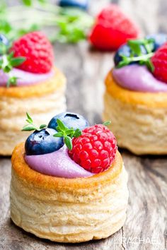 three desserts with berries and blueberries on top of each other, sitting on a wooden table