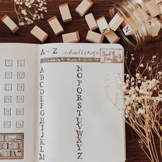 an open book sitting on top of a wooden table next to flowers and other items