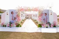 an outdoor ceremony setup with flowers and candles on the ground, in front of a white backdrop