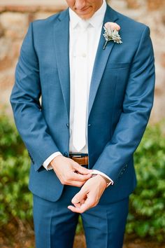 a man in a blue suit and white shirt is holding his hand on his lapel